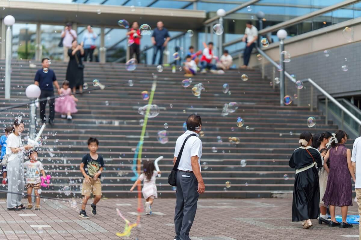 SAYAKAホール前で巨大シャボン玉に集まる子どもたち
