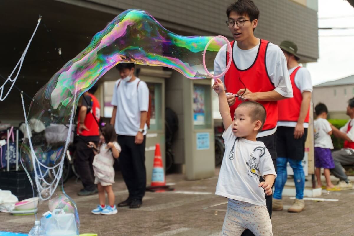 巨大シャボン玉に挑戦する男の子とスタッフ